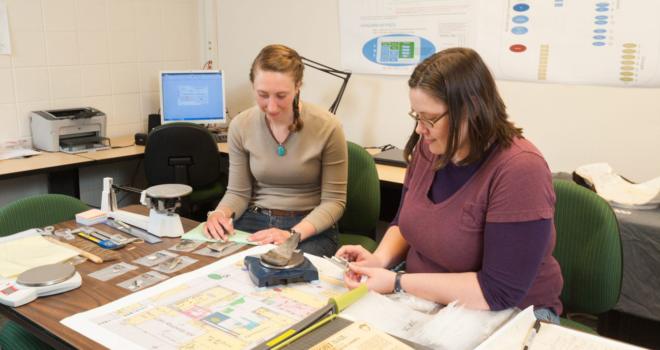 Students working in the Archaeology Lab, weighing an artifact on a scale
