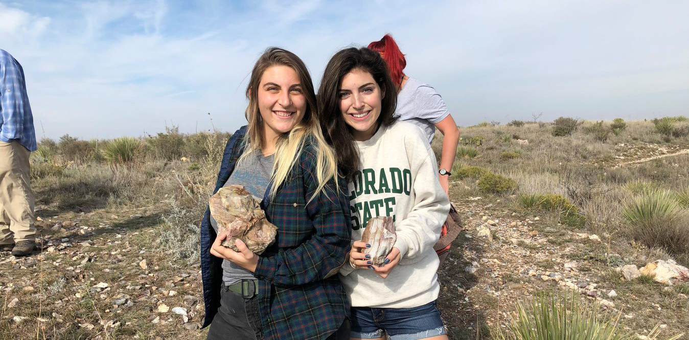 Two anthropology students holding rocks they've found in the field