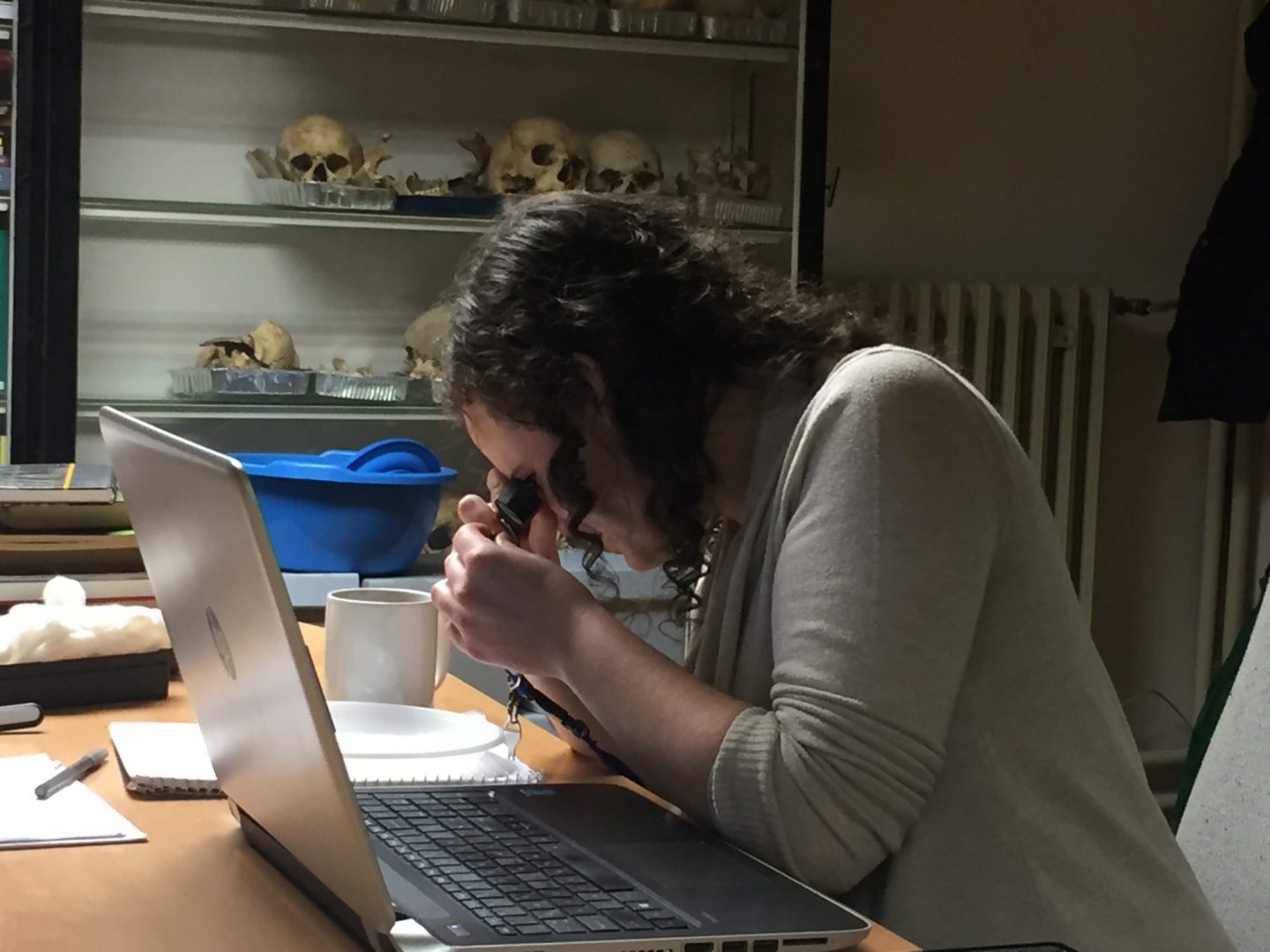 Woman looking through a magnifying scope at an artifact
