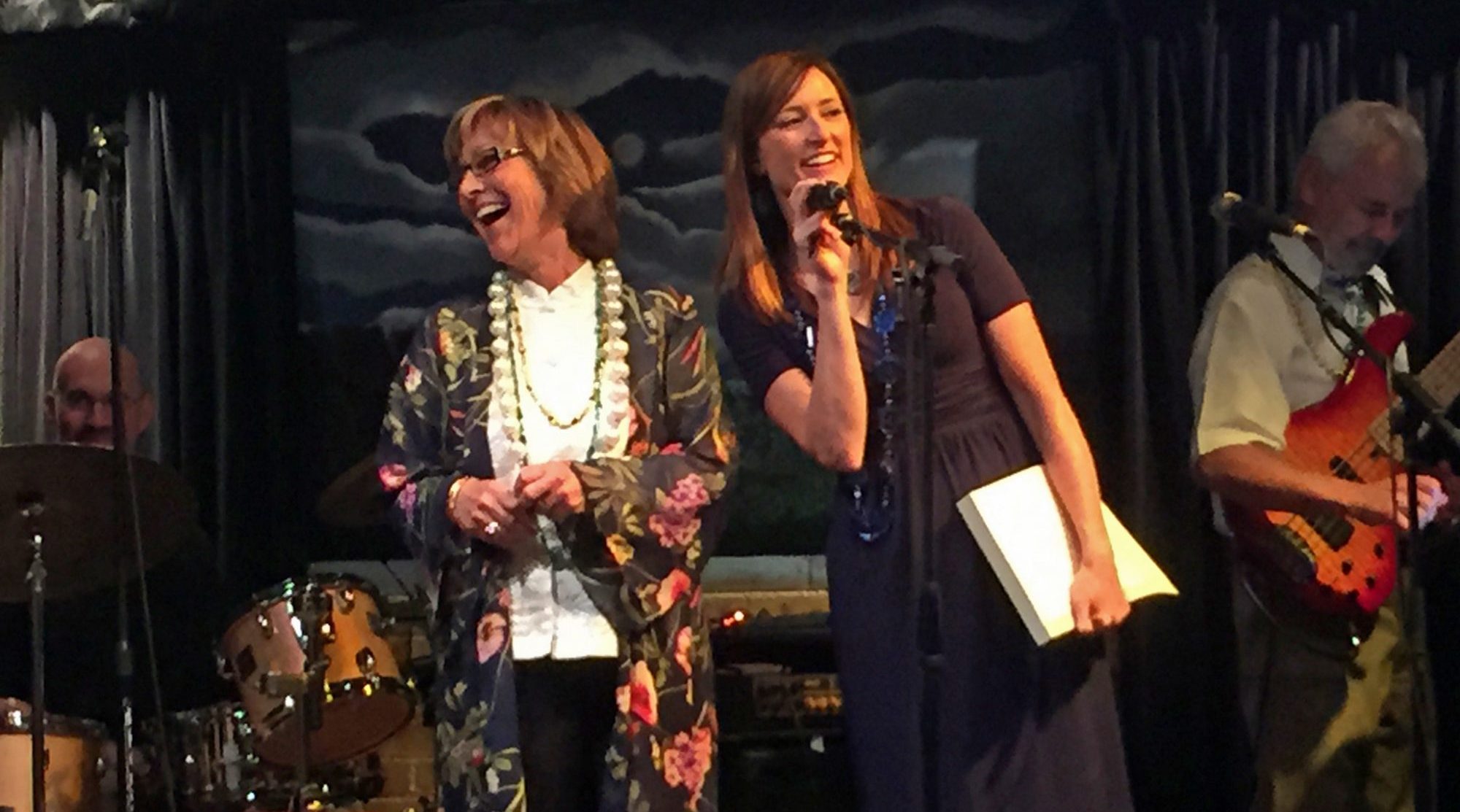 Two professors laughing on a stage during book release party