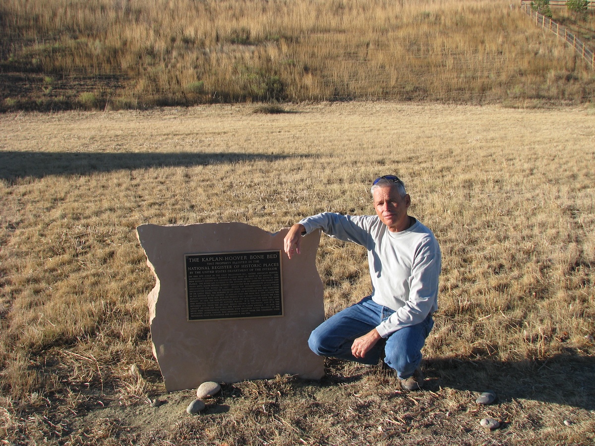 Professor squatting next to historical marker