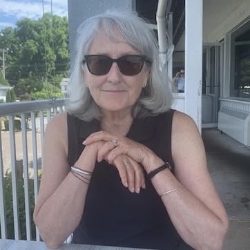 Woman, seated, outdoors with hands folded