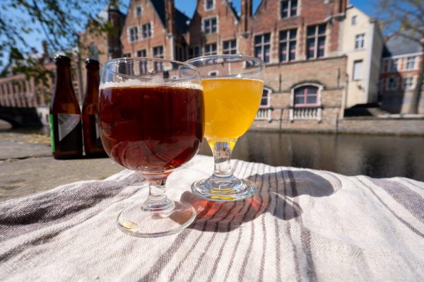Tasting of Belgian beer on open cafe or bistro terrace with view on medieval houses and canals in Bruges, Belgium in sunny day