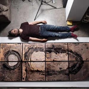 Kei Ito lying down in the studio next to a large photograph.