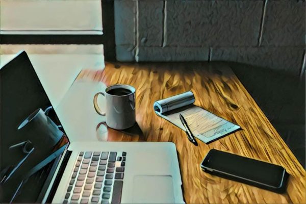 desk with laptop, notepad, phone, and cup of coffee
