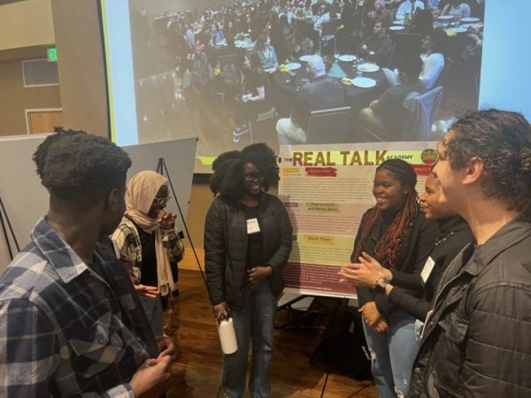 Students from the "Real Talk" URA chatting in a circle in front of a poster at MURALS