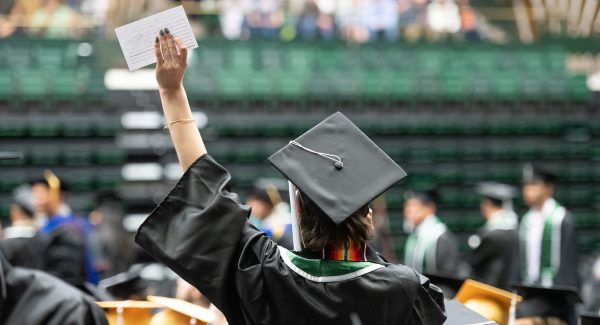 Student holding up their hand to wave at commencement