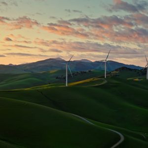 Aerial photograph of green hills in Altamont, California. The hills are dotted with windmills.