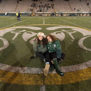 Jennifer Clary and her daughter sit in the middle of the field at Hughes Stadium