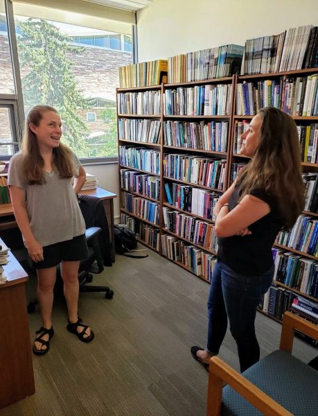 two women standing in an office in front of bookshelves talking