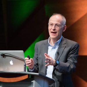 man (Zeke Emanuel) giving a lecture behind a computer