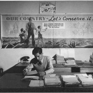 An Agricultural Adjustment Administration representative in his office, Taos County, New Mexico, December 1941. The agency was created under the New Deal to reduce farm surpluses and manage production.