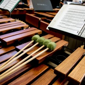 A marimba with four mallets is pictured next to sheet music
