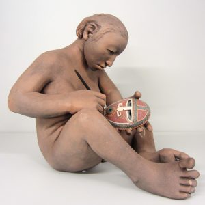 An image of cermaic pieces that is a native American person carving a maks