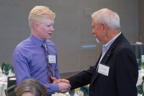 Student shakes the hand of the donor who funds the scholarship he recieved