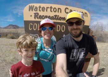 Melissa Raguet-Schofield smiling with her husband and son during a run at Waterton Canyon
