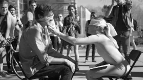 Devan Kallas sits blindfolded on the LSC Plaza, touching the face of a student who sat down across from her.