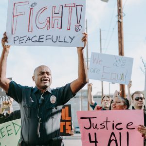 Protesters holding up signs that read "Fight peacefully" and "Justice 4 all"