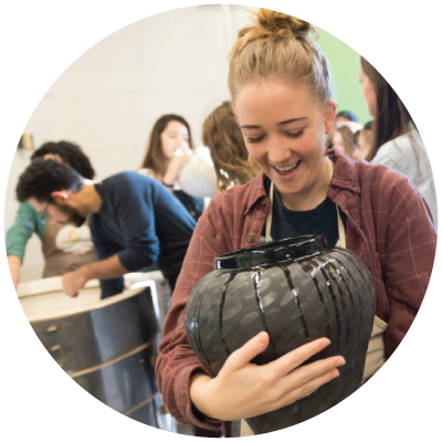 Student excitedly looks over her vase fresh out of the kiln