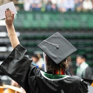 Student holding up their hand to wave at commencement