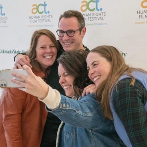 ACT Film Festival patrons take a selfie in front of a white banner for the festival.