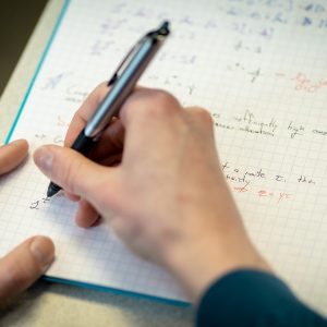 Hand of a student writing notes in an economics class