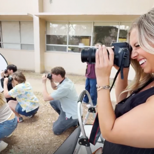 Four students take photos of a fashion shoot for a journalism class