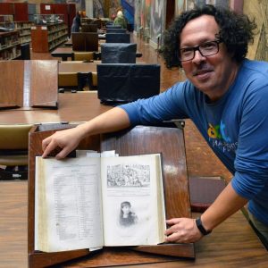Antonio Pedros-Gascon leans over one of the volumes of El Album de la Mujer in Mexico City