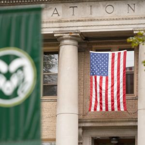 Green CSU logo flag in the foreground with U.S. flag in the background