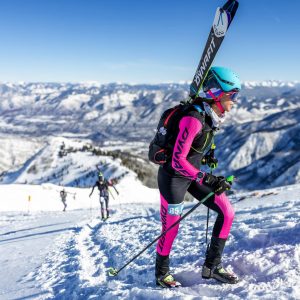 Woman walking up mountain with skis on back