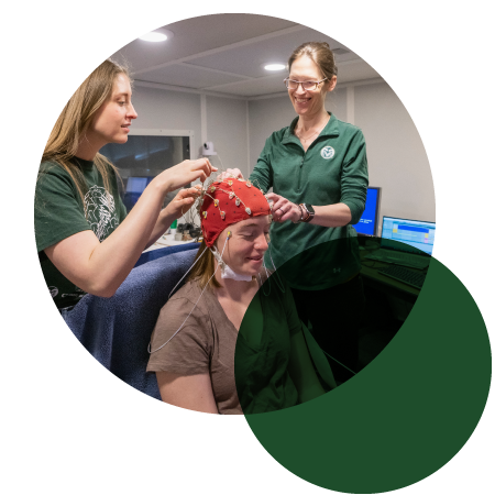 Blythe LaGasse and a student hook up a student to a machine to measure brainwaves