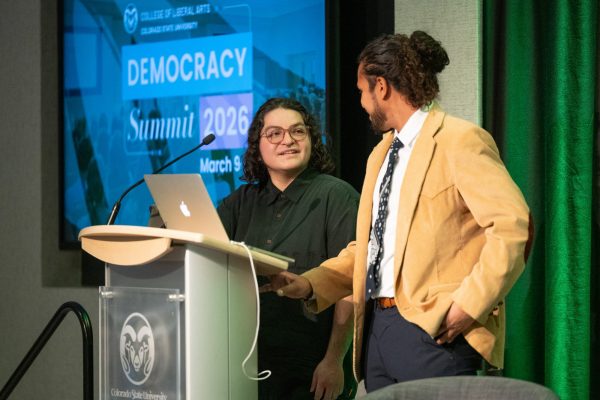 Two people stand at a podium presenting their work at the CLA Democracy Summit