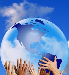 Diverse hands supporting a blue globe against a bright sky, symbolizing unity and global responsibility.