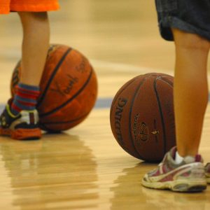 Children shown standing from the knees down with basketballs at their feet.